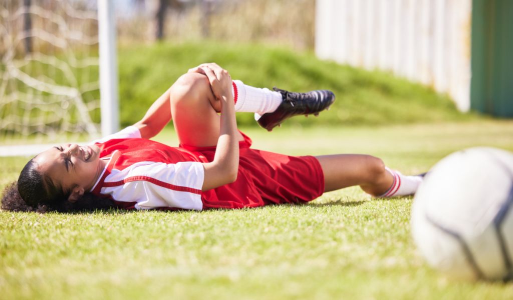 Female soccer player on the ground holding her knee