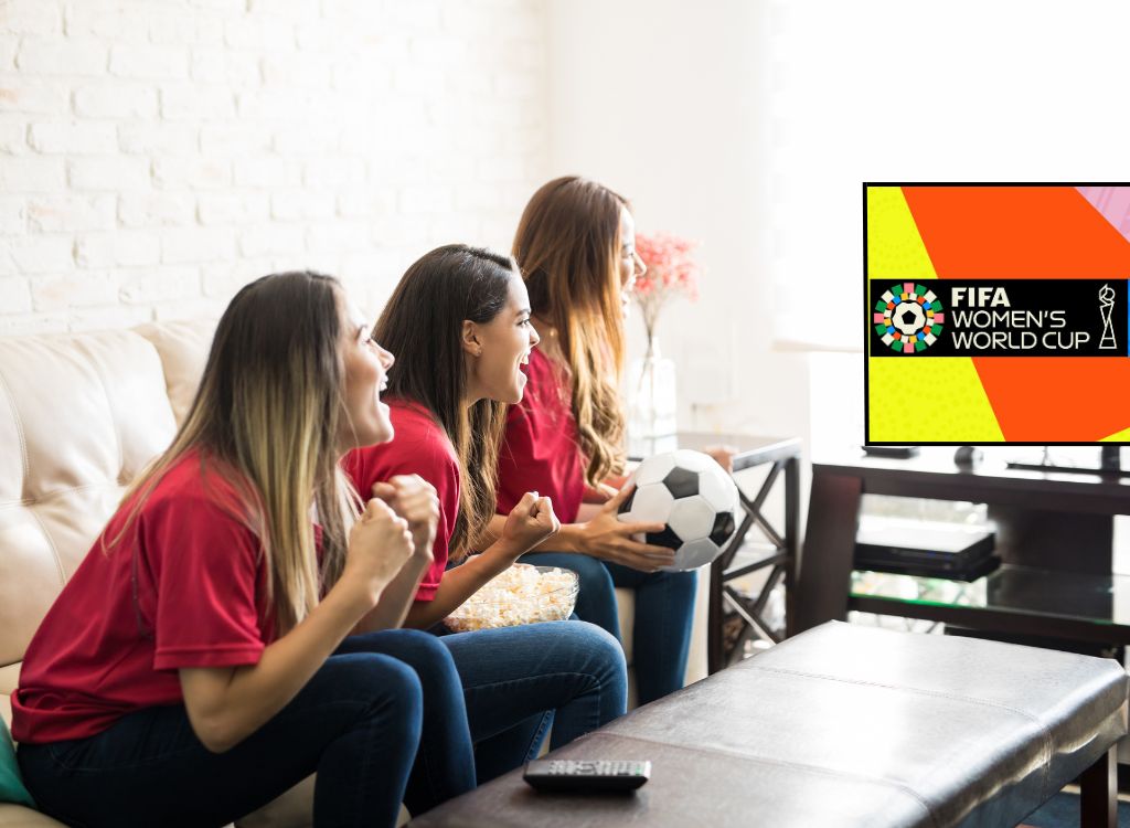 Three girls sitting on sofa watching women's world cup on TV.