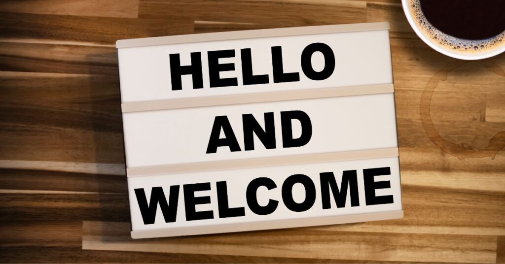 Hello and Welcome sign on wood background and coffee cup upper right corner