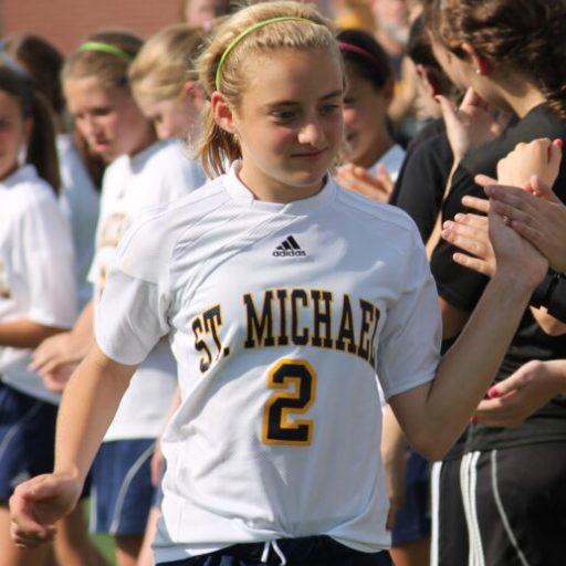 Maddie Pierce in St. Michaels uniform clapping hands with teammates.