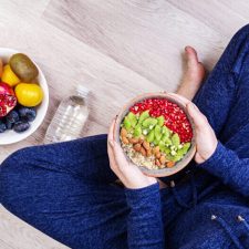 Fitness and healthy lifestyle concept. Female is resting and eating a healthy oatmeal after a workout. Top view.