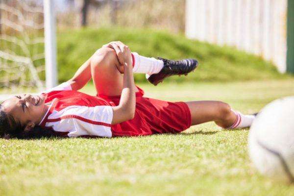 Female soccer player on the ground holding her knee