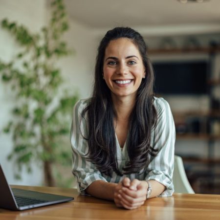 Happy dark-haired woman at desk with laptopr.