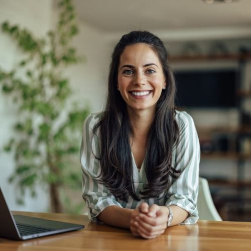 Happy dark-haired woman at desk with laptopr.