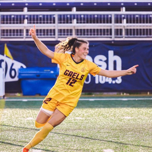 Christie Gray running with arms out celebrating scoring a goal