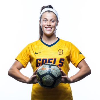 Christie Gray in soccer uniform for Queens College in Canada holding a soccer ball.
