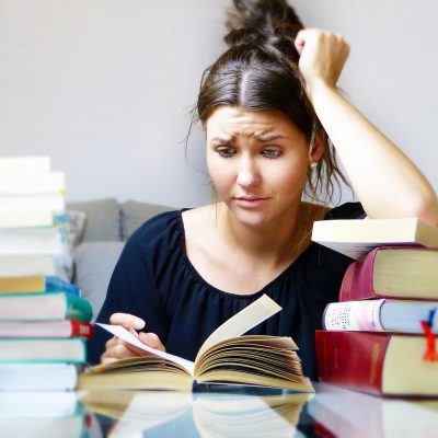 high school girl at desk looking books with a stresful look on her face.